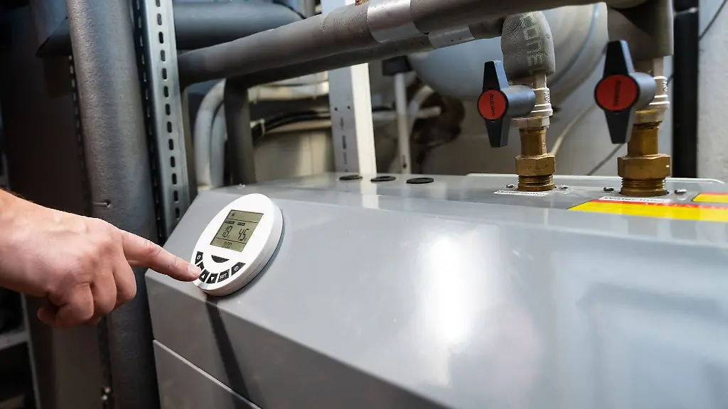 Ein-Mann-bedient-eine-Luftwaermepumpe-die-im-Keller-eines-Wohnhauses-steht