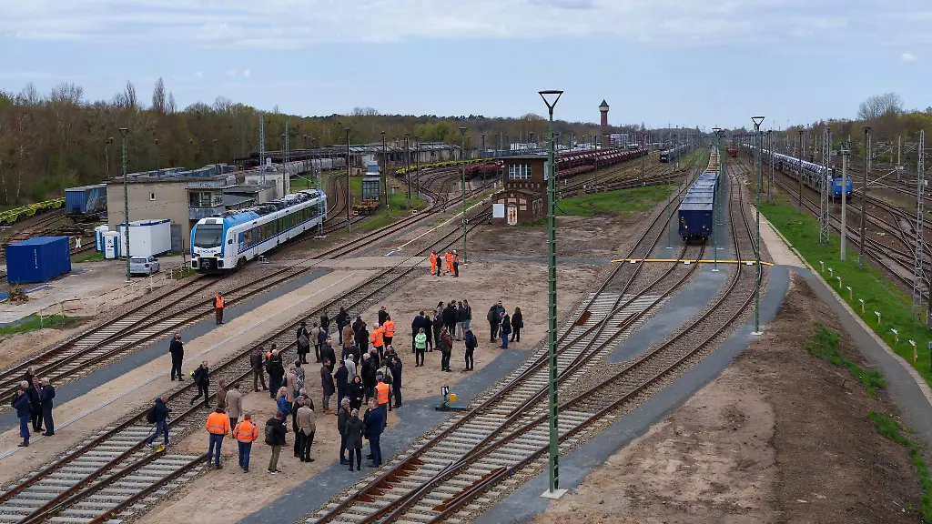 Gaeste-der-Veranstaltung-beobachten-einen-auf-die-neuen-Gleise-fahrenden-Gueterzug