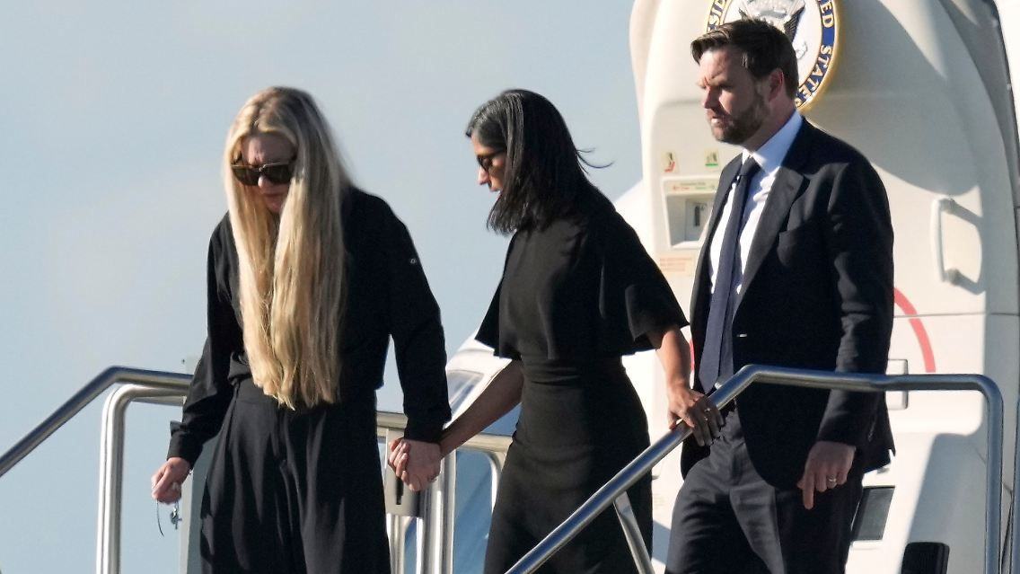 Usha Vance hält Erika Kirks Hand. Dahinter JD Vance.