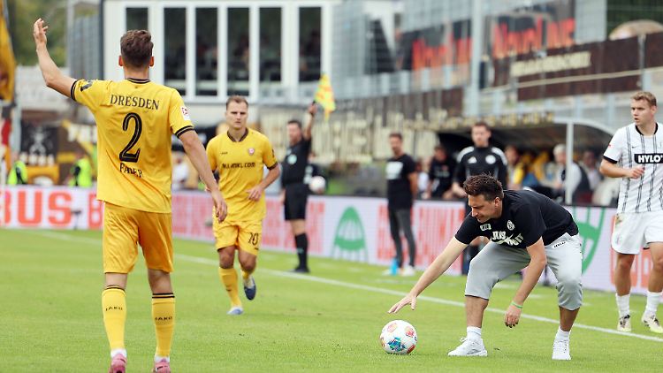 Elversberg-Trainer Vincent Wagner stoppt den Ball mit der Hand. Das Spiel ist zum Glück unterbrochen.