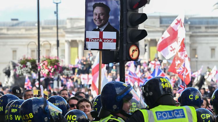 Ein Demo-Teilnehmer hält ein Schild mit einem Foto von Elon Musk in die Höhe.