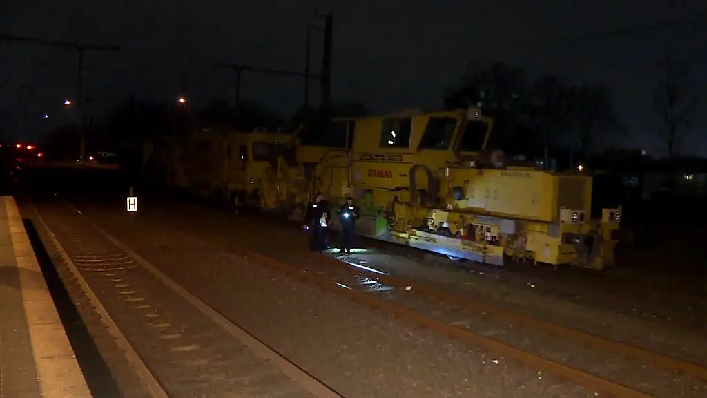 Einsatzkraefte-der-Polizei-untersuchen-an-eine-Unfallstelle-neben-einem-Zug-die-Bahngleise