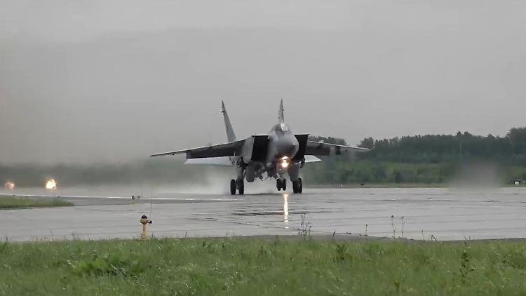 Ein MiG-31-Kampfjet startet, die Landebahn ist nass.