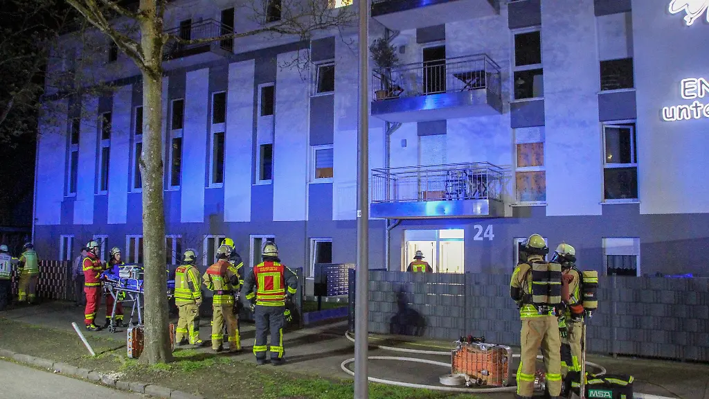 Feuerwehrleute-und-Rettungskraefte-stehen-vor-einem-Haus-fuer-betreutes-Wohnen-in-dem-ein-Brand-ausgebrochen-war