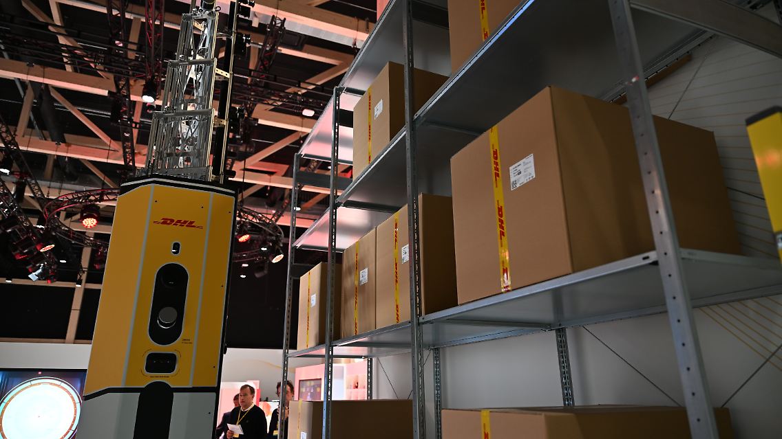 Ein Logistik-Roboter namens DexoryView der britischen Roboter-Firma Dexory scannt im DHL-Innovationszentrum ein Regal mit DHL-Paketen ab. Der Roboter verfügt über Teleskop-Stangen, die bis zu 14 Meter hoch reichen.