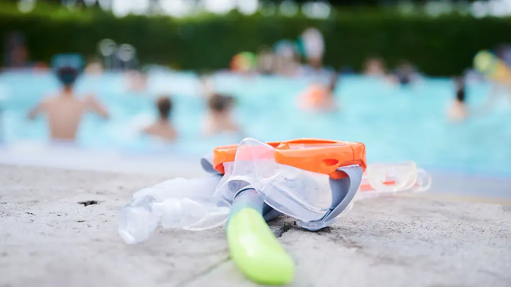 Eine-Taucherbrille-und-Schnorchel-liegen-in-einem-Schwimmbad-am-Beckenrand