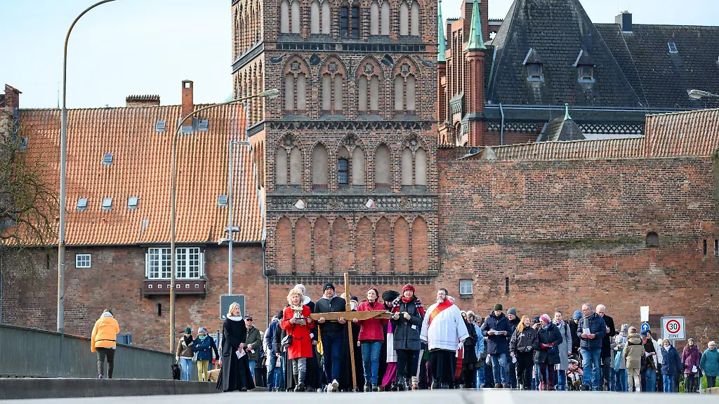 Glaeubige-tragen-ein-Holzkreuz-ueber-die-Burgtorbruecke