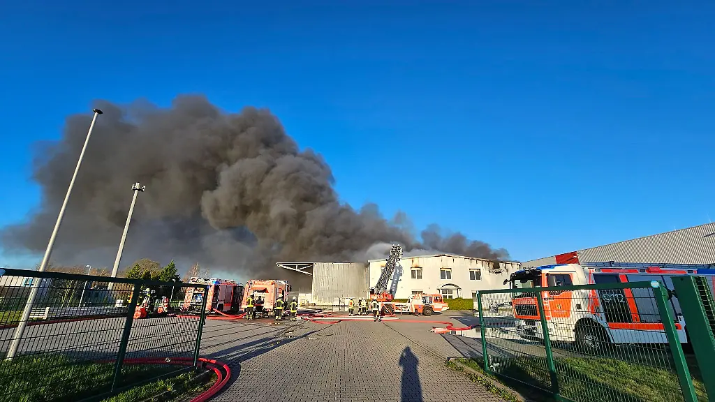Eine-Rauchwolke-steigt-ueber-einer-brennenden-Lagerhalle-auf