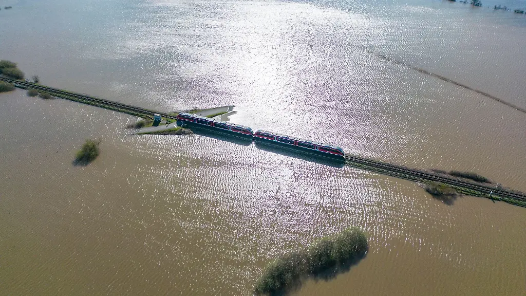 Ein-Regionalzug-faehrt-ueber-eine-ueberflutete-Wiese