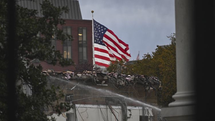 Am Weißen Haus weht die US-Flagge über Ruinen.