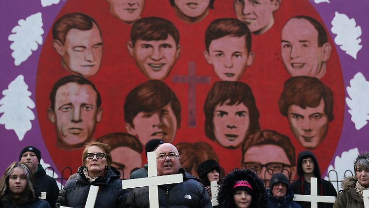 Britische Soldaten schießen am 30. Januar 1972 auf Teilnehmer eines katholischen Protestmarschs. Die Konterfeis der Opfer werden hier bei einer Trauerprozession gezeigt.
