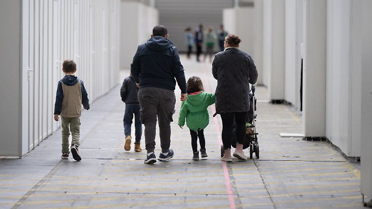 Eine Flüchtlingsfamilie geht durch die zu einer Massenunterkunft umfunktionierte Messehalle in Frankfurt.