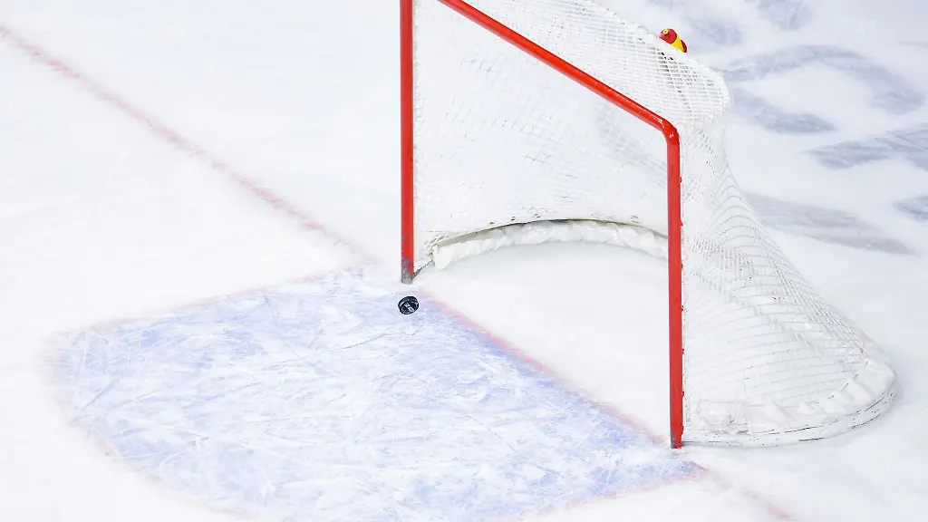 Ein-Puck-fliegt-in-ein-leeres-Eishockey-Tor
