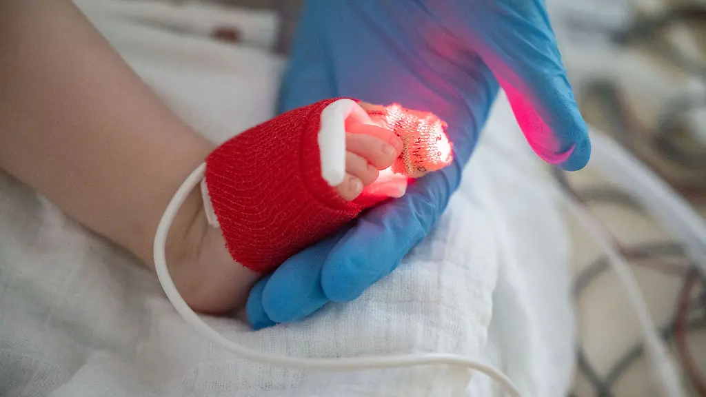 Eine-Intensivpflegerin-haelt-auf-der-Kinder-Intensivstation-den-Fuss-eines-am-Respiratorischen-Synzytial-Virus-RS-Virus-oder-RSV-erkrankten-Patienten