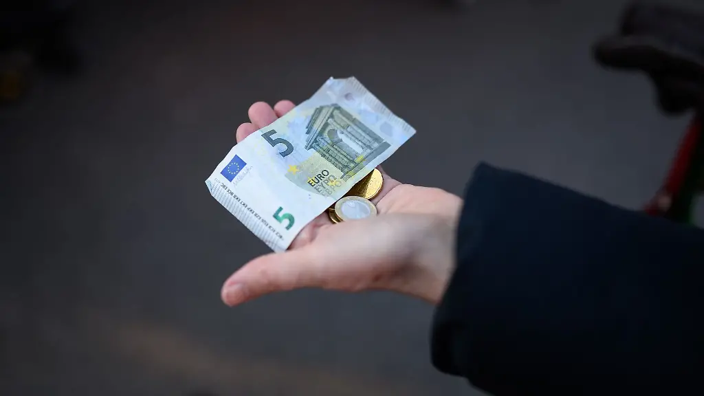 Eine-Frau-haelt-das-Bargeld-fuer-ihren-Einkauf-in-der-Hand-bereit