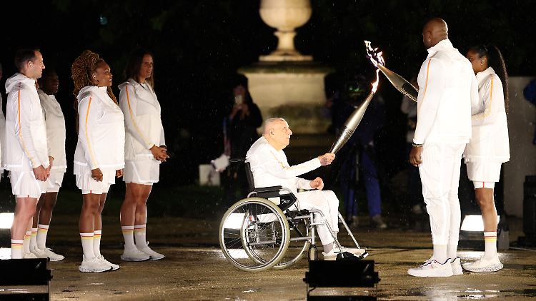 Charles Coste übergibt 2024 das olympische Feuer an Marie-Jose Perec und Teddy Riner.