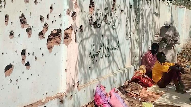 Opfer des Krieges: Vertriebene Sudanesen neben einer von Kugeln durchlöcherten Wand.