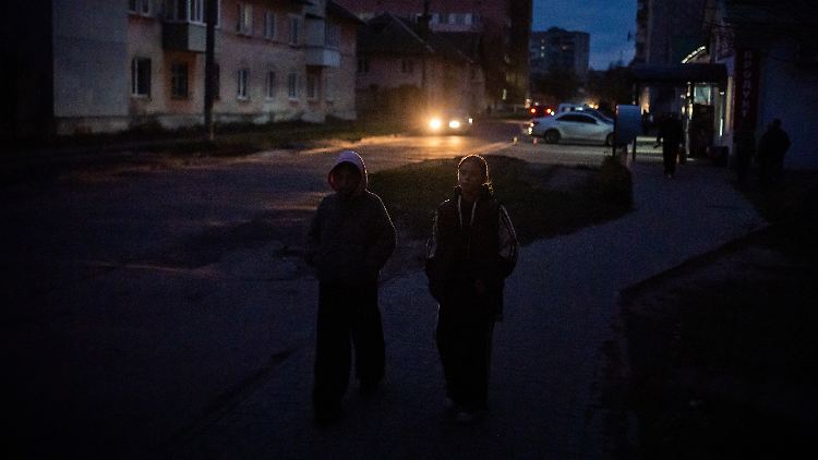 Kinder gehen während eines Stromausfalls durch eine dunkle Wohnstraße. 