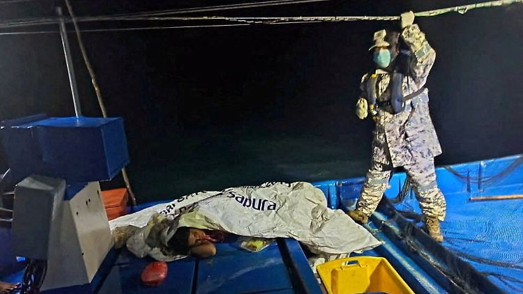 Ein malaysischer Militärangehöriger kümmert sich um einen geretteten Überlebenden.