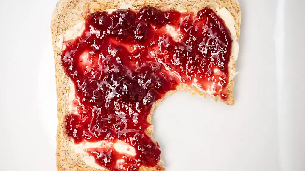 Ein-Toastbrot-mit-Himbeermarmelade-liegt-auf-auf-einem-Teller