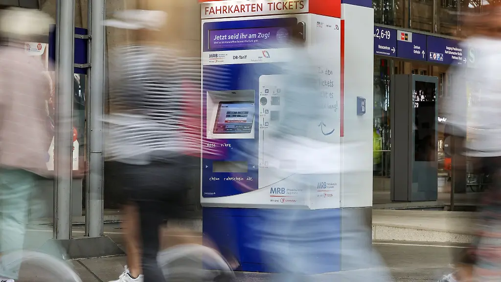 Passagiere-gehen-an-einem-Bahnhof-an-Fahrkartenautomaten-vorbei