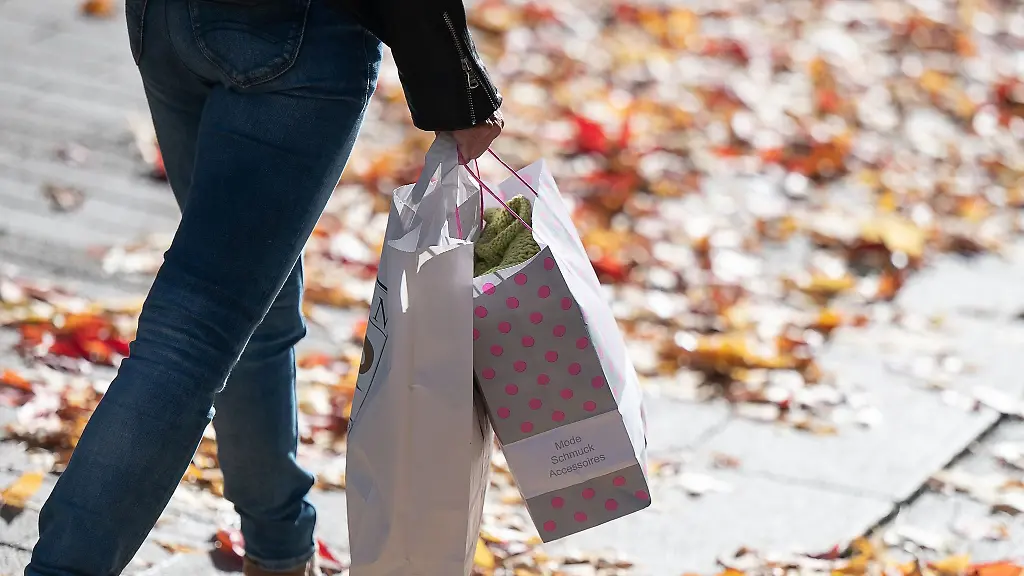 Eine-Frau-geht-mit-Einkaufstueten-ueber-eine-Strasse