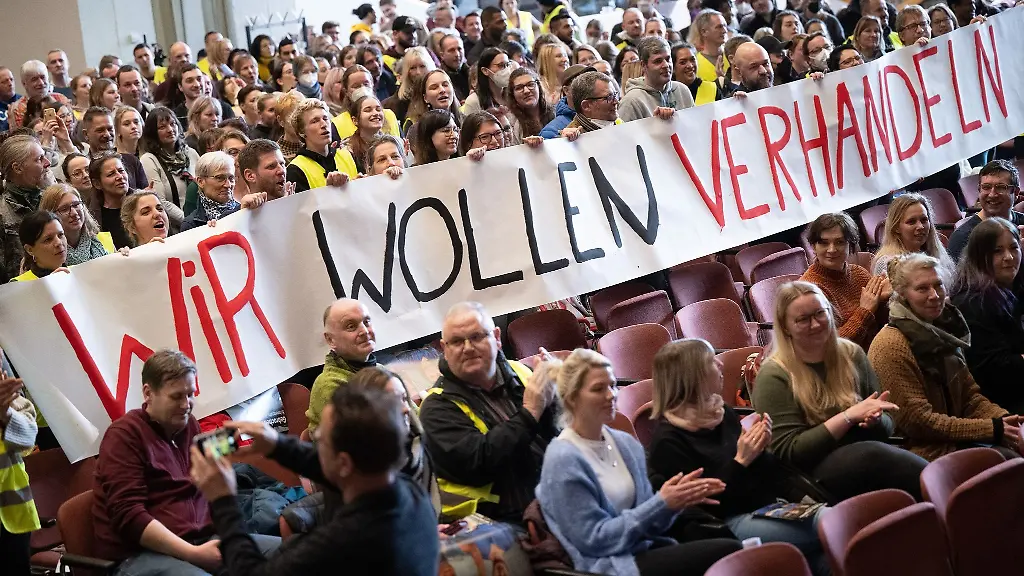 Teilnehmende-halten-einen-Banner-mit-der-Aufschrift-Wir-wollen-verhandeln-hoch