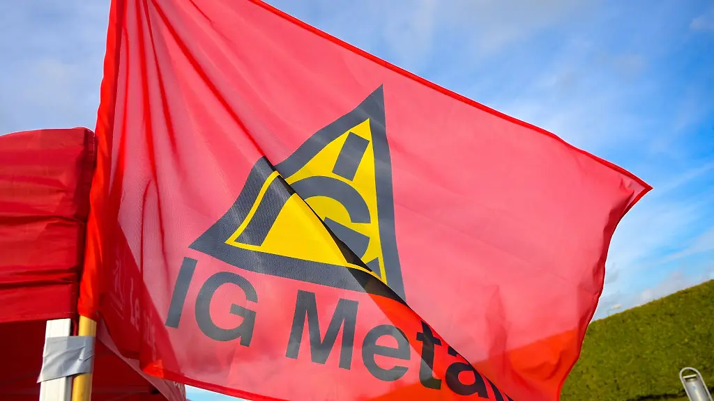 Eine-Fahne-mit-dem-Logo-der-IG-Metall-haengt-an-einem-Stand