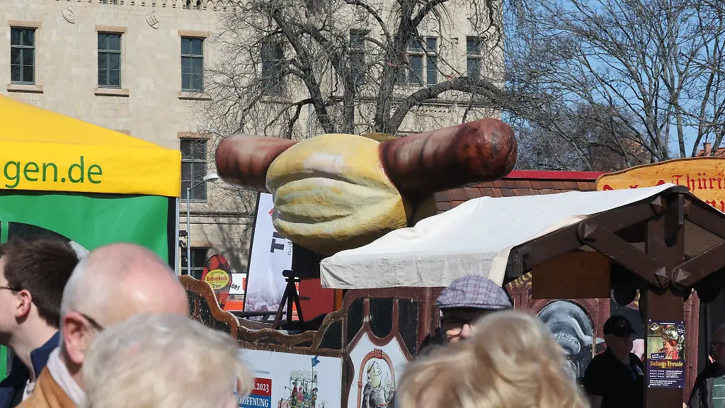 Eine-symbolische-Bratwurst-ist-auf-dem-Dach-eines-Standes-montiert-beim-Festival-Rostkultur-2023-zur-Eroeffnung-der-Grillsaison-in-Thueringen