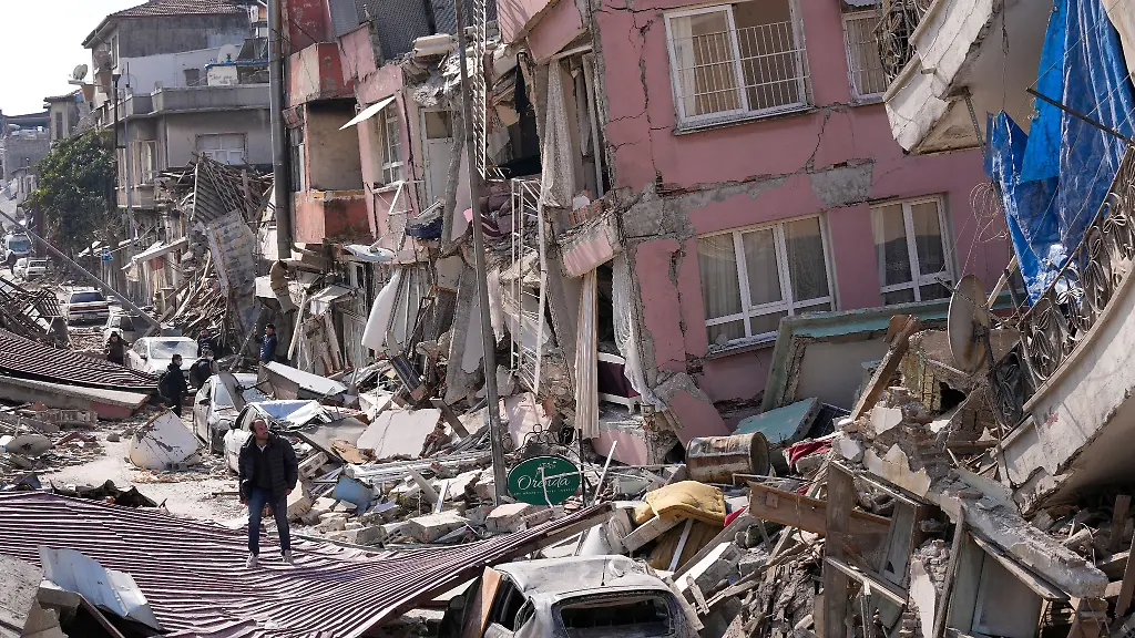 Ein-Mann-geht-Anfang-Maerz-ueber-die-Truemmer-eingestuerzter-Gebaeude-in-Hatay