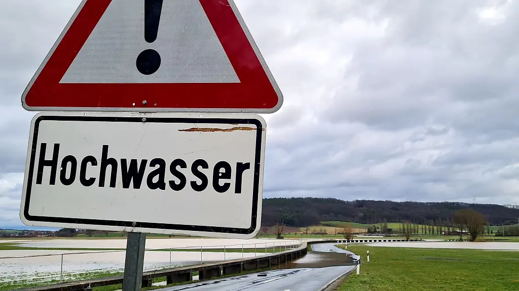 Die-Strasse-zwischen-Hemmendorf-Gemeinde-Untermerzbach-Landkreis-Hassberge-Unterfranken-und-Lahm-Gemeinde-Itzgrund-Landkreis-Coburg-Oberfranken-ist-ueberflutet-Eine-Schild-warnt-vor-Hochwasser