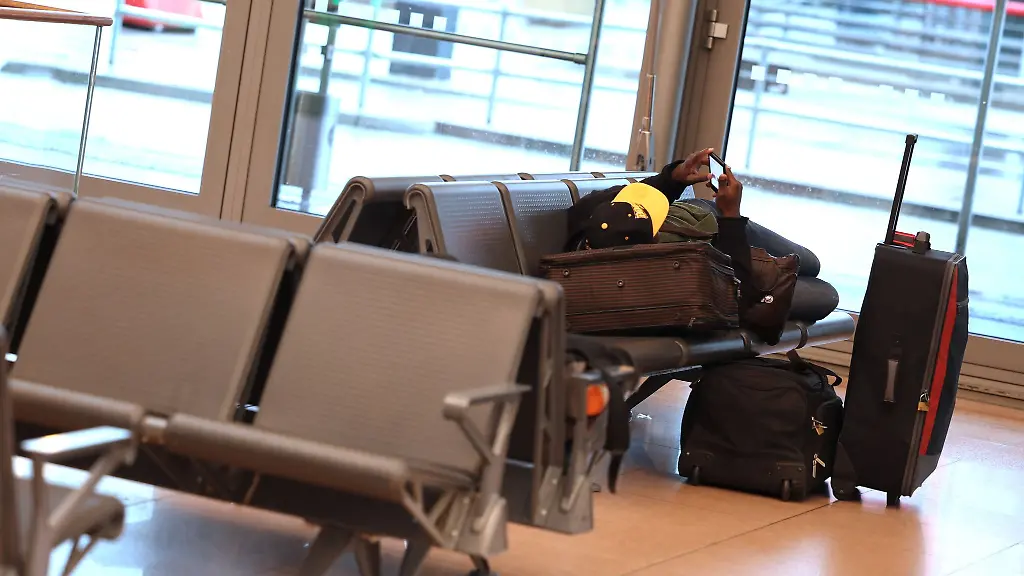 Ein-Reisender-liegt-auf-einer-Bank-im-Wartebereich-des-Terminal-1-im-Flughafen-Hamburg
