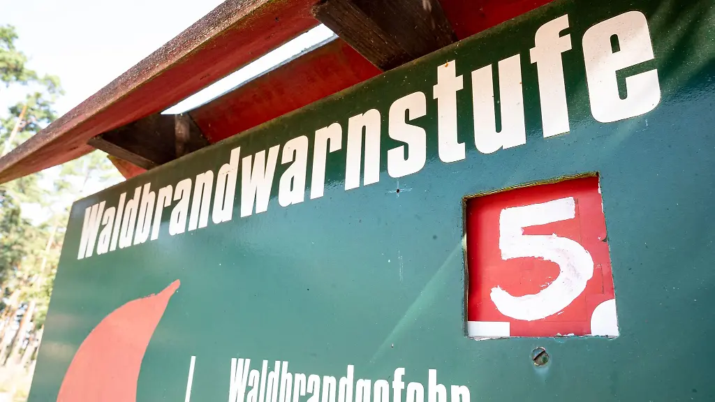 Eine-Tafel-vor-einem-Waldstueck-weist-auf-die-hoechste-Waldbrandwarnstufe-fuenf-hin