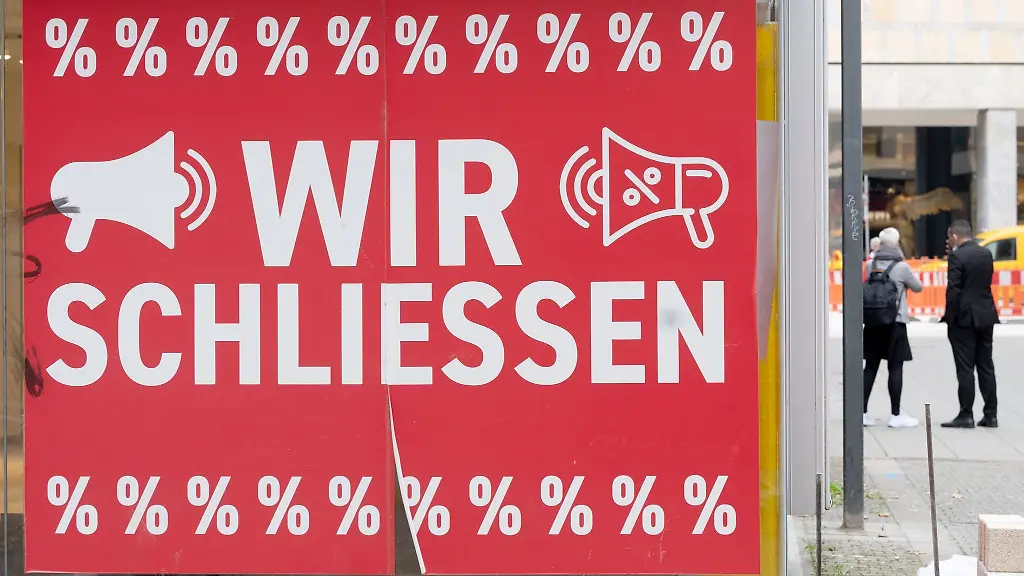 Ein-Schild-mit-dem-Hinweis-Wir-schliessen-haengt-an-einem-Bekleidungsgeschaeft