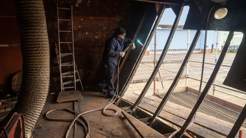 Ein-Arbeiter-arbeitet-am-Segelschulschiff-Greif-das-auf-dem-Gelaende-der-Volkswerft-liegt