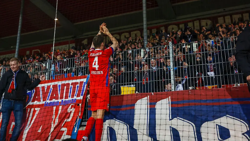 Der-Heidenheimer-Tim-Siersleben-M-feiert-oben-auf-dem-Zaun-mit-den-Heimfans-den-1-0-Sieg