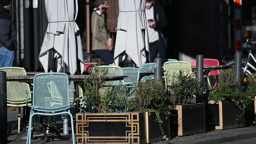 Tische-und-Stuehle-sind-vor-einem-Lokal-auf-dem-Buergersteig-aufgestellt