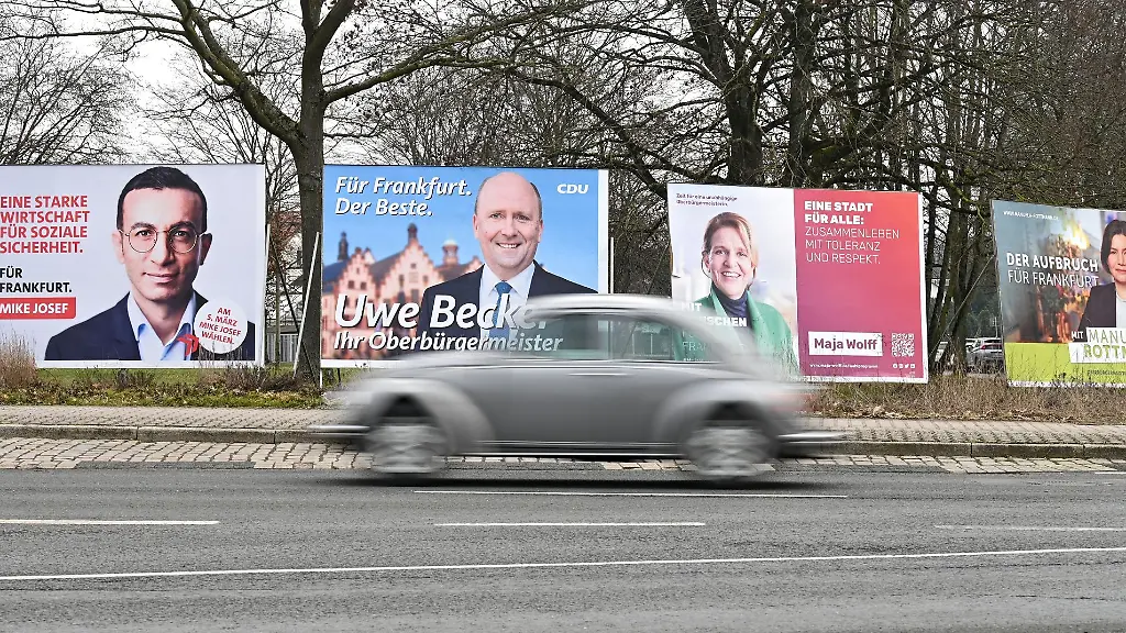 Ein-Auto-faehrt-im-Stadtteil-Sachsenhausen-an-Wahlplakaten-der-Kandidaten-Mike-Josef-SPD-l-r-Uwe-Becker-CDU-Maja-Wolff-unabhaengig-und-Manuela-Rottmann-Buendnis-90-Die-Gruenen-vorbei