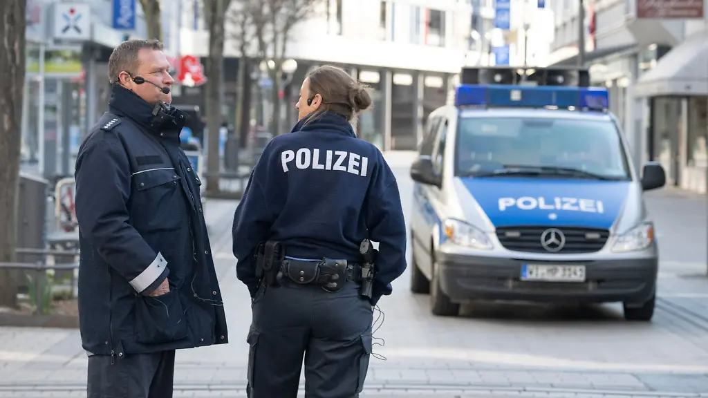 Ein-Polizist-und-eine-Polizistin-stehen-in-der-Innenstadt