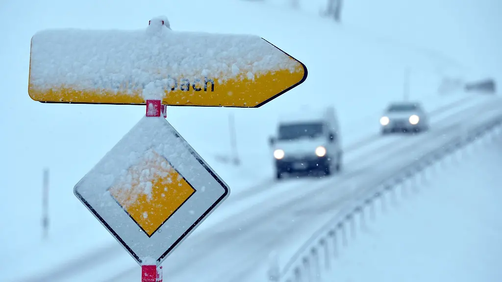 Neuschnee-bedeckt-ein-Vorfahrtsschild-und-einen-Wegweiser
