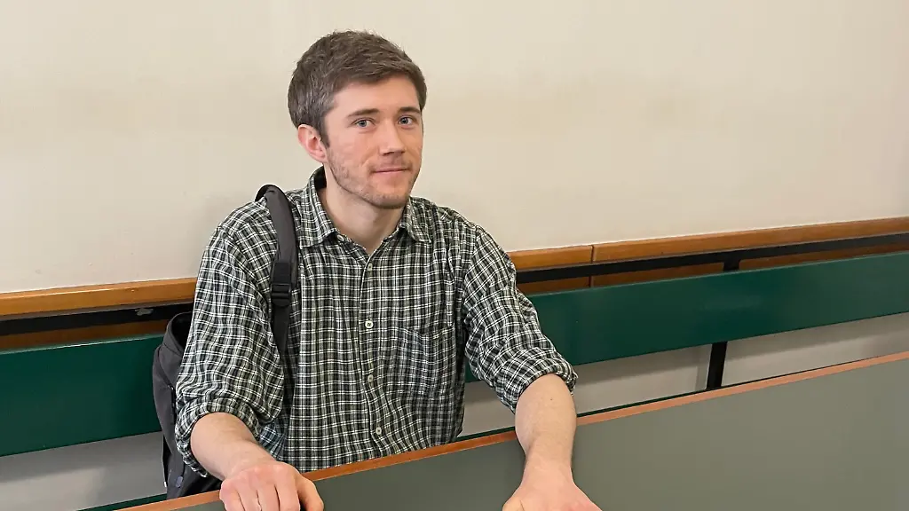 Klimaaktivist-Henning-Jeschke-sitzt-festgeklebt-an-einem-Tisch-in-einem-Raum-des-Amtsgericht-Berlin-Tiergarten