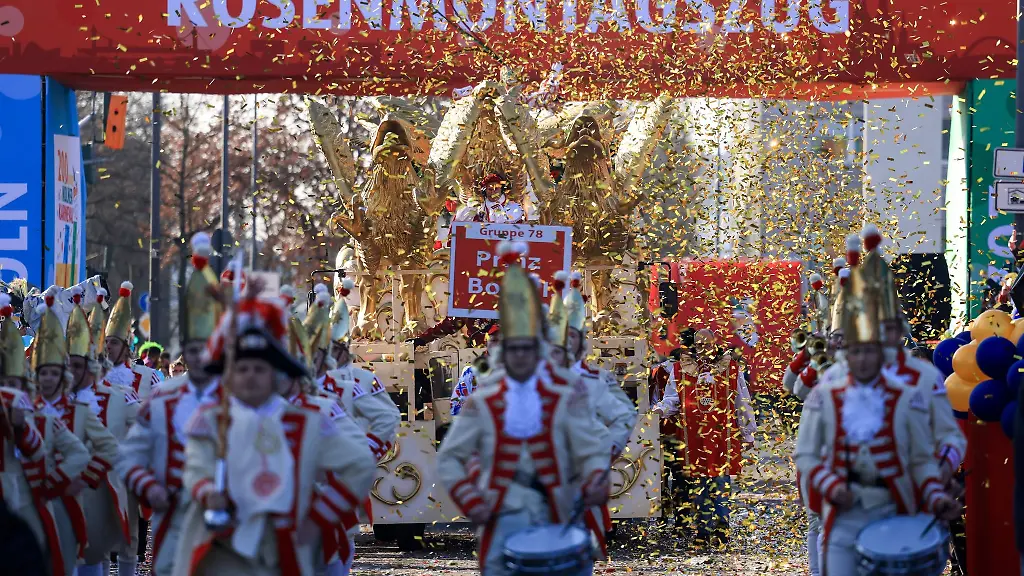 Ein-Spielmannszug-geht-im-Konfettiregen-vor-dem-Schriftzug-Rosenmontagsszug-entlang