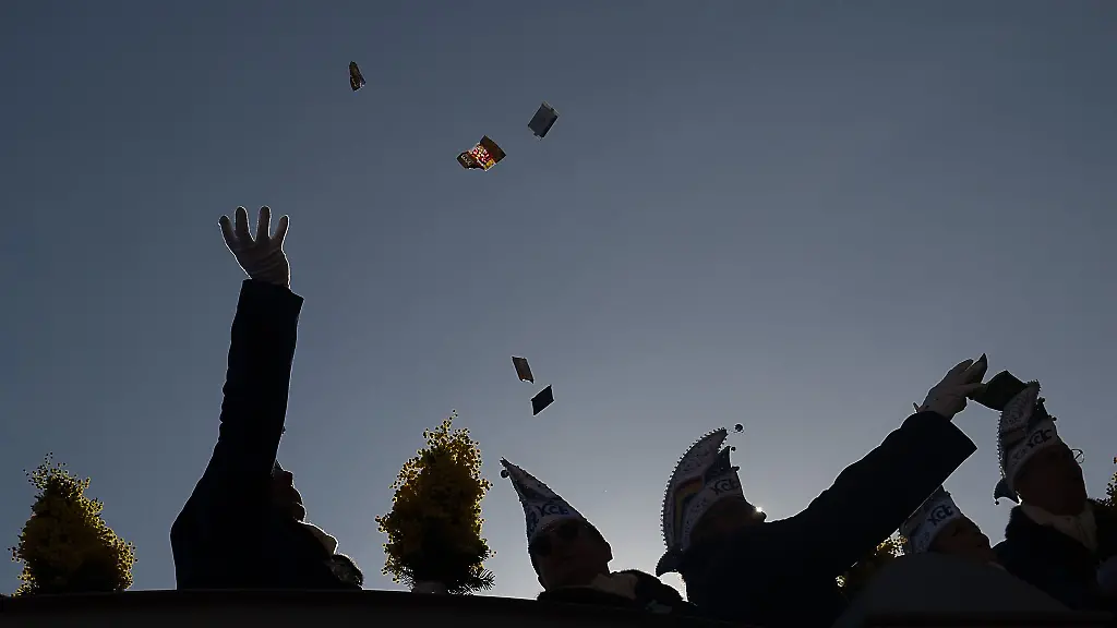 Teilnehmer-eines-Rosenmontagsumzugs-werfen-Suessigkeiten-von-einem-Wagen