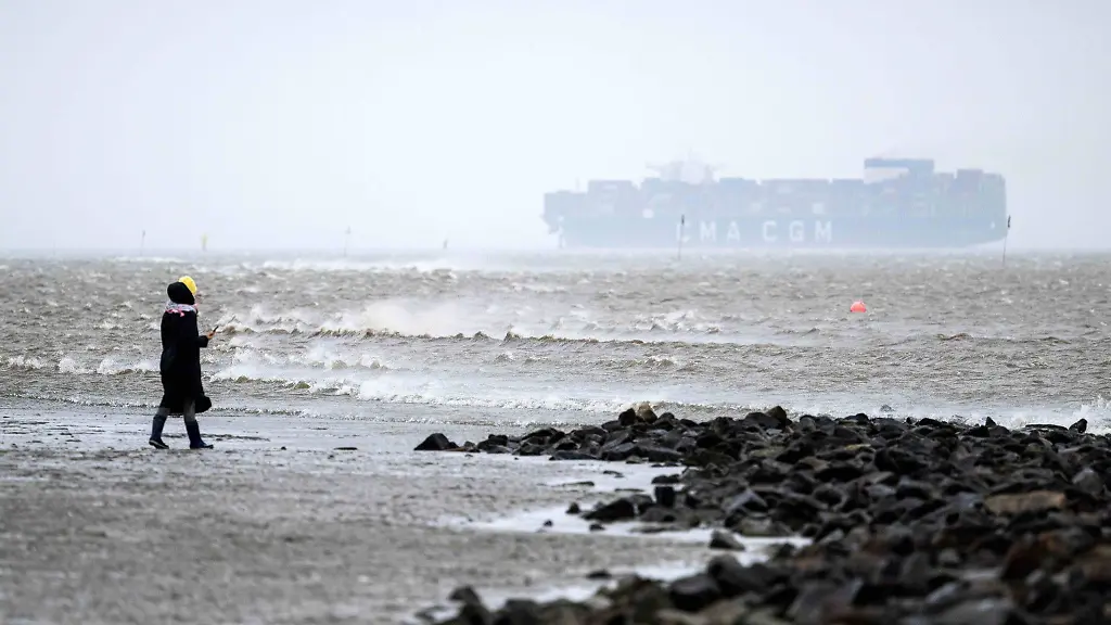 Eine-Frau-steht-bei-stuermischem-Wetter-am-Strand-von-Cuxhaven