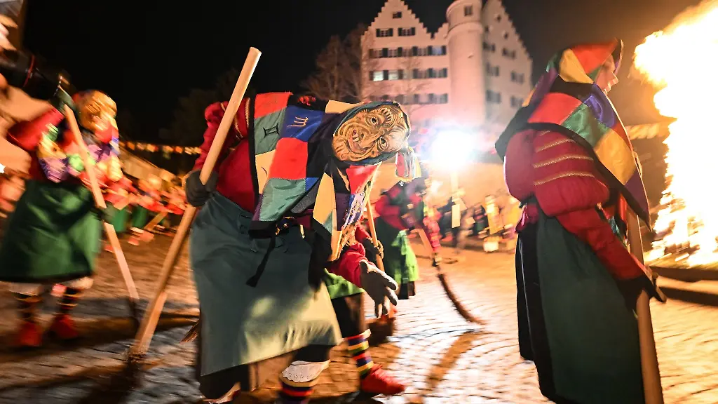 Dutzende-Eckhexe-der-Narrenzunft-Aulendorf-tanzen-am-fruehen-Abend-um-ein-Feuer-herum