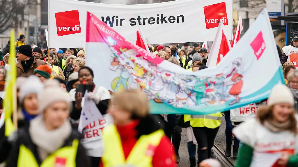 Streikende-halten-bei-einer-Demonstration-ein-Transparent-in-die-Hoehe