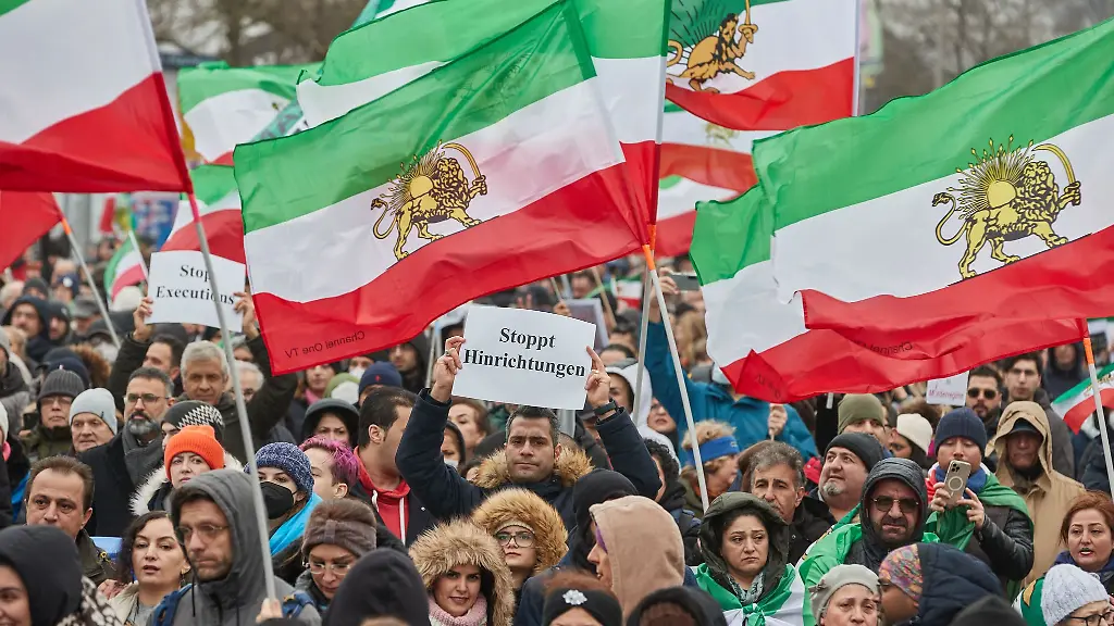 Demonstrierende-gegen-das-iranische-Regime-halten-Flaggen-und-ein-Transparent-Stoppt-Hinrichtungen