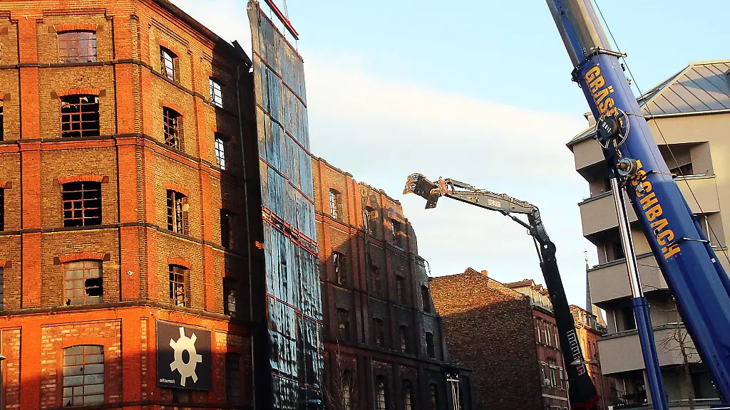 Mit-einem-Abrissbagger-wird-die-Aussenfassade-des-ausgebrannten-Gebaeudes-Stueck-fuer-Stueck-abgetragen