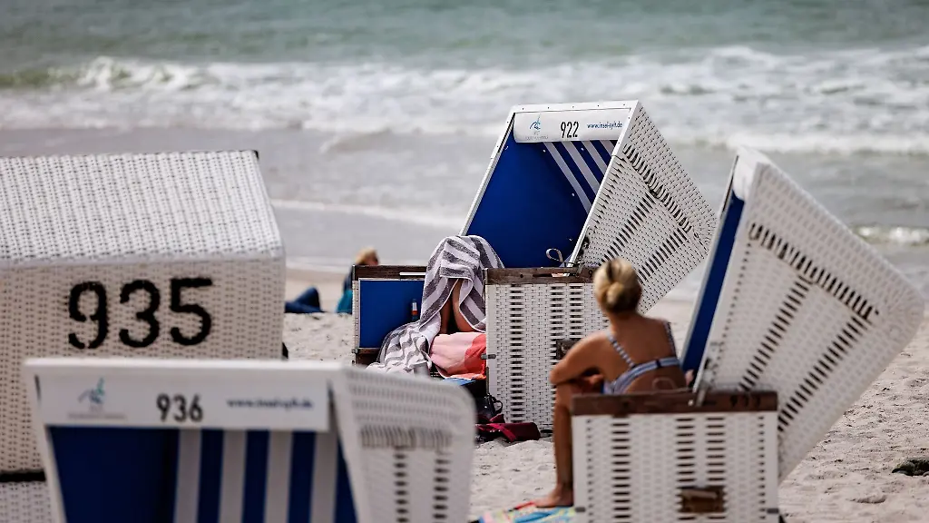 Besucher-des-Strands-geniessen-die-Sonne-in-Strandkoerben