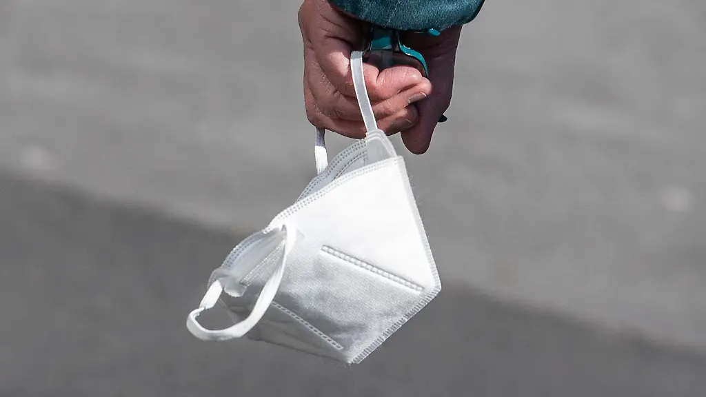 Ein-Passant-traegt-eine-FFP2-Maske-in-der-Hand